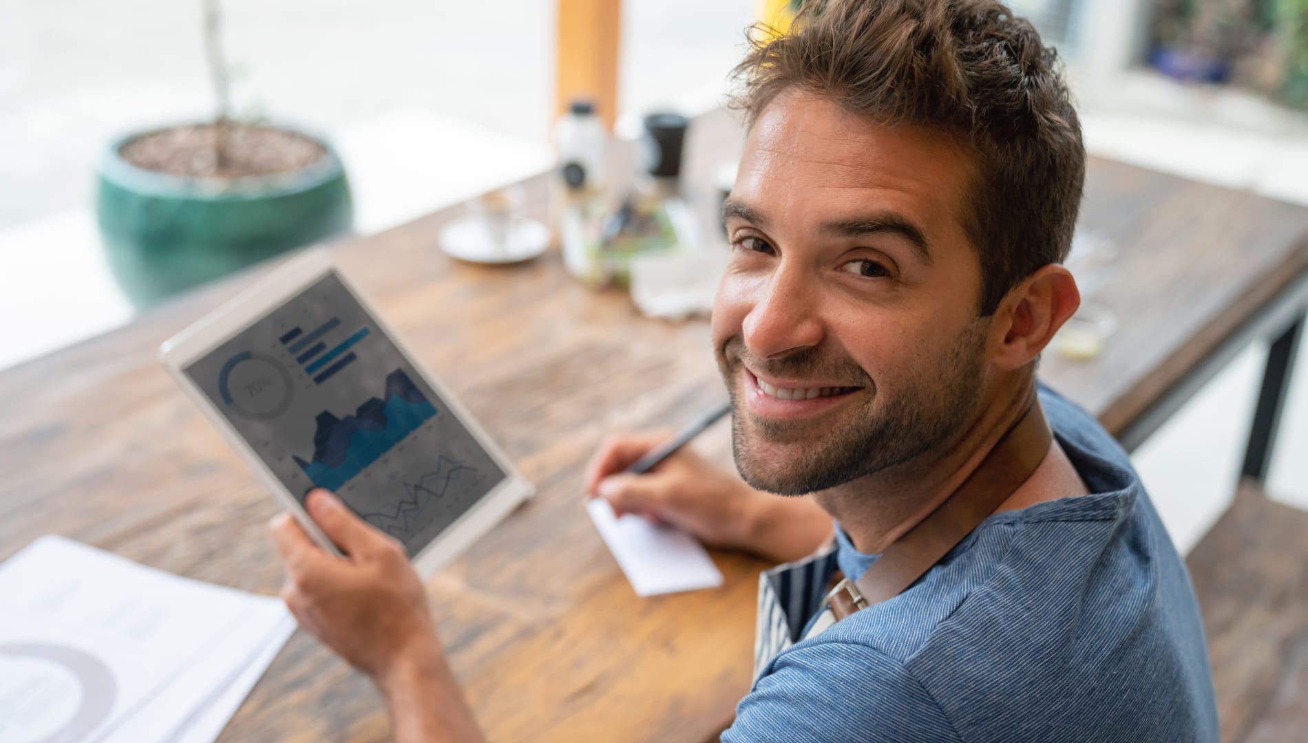 Man holding tablet looking over shoulder and smiling